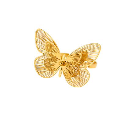 A gold butterfly-shaped ring with an open, wireframe design, displayed on a clean white background with decorative white baby's breath flowers in the corners.